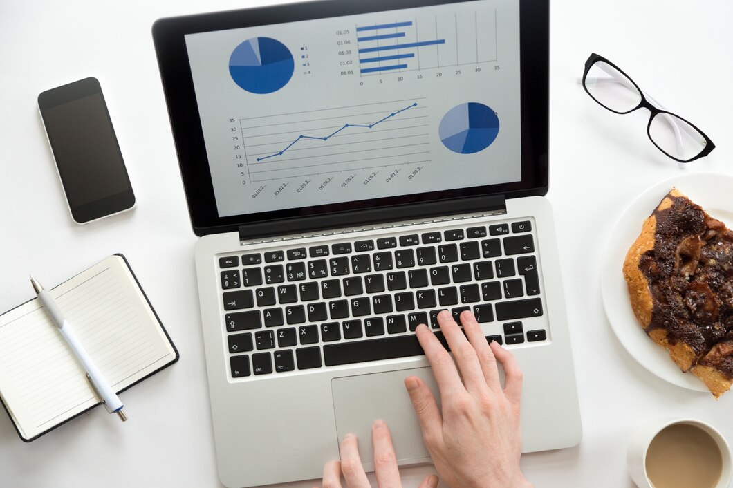 A laptop with an SEO diagram, office supplies, glasses, and a mobile phone on a desk.